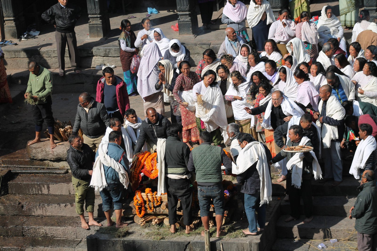 Ceremonia de la muerte a orillas del río Bagmati en Nepal, con flores amarillas.