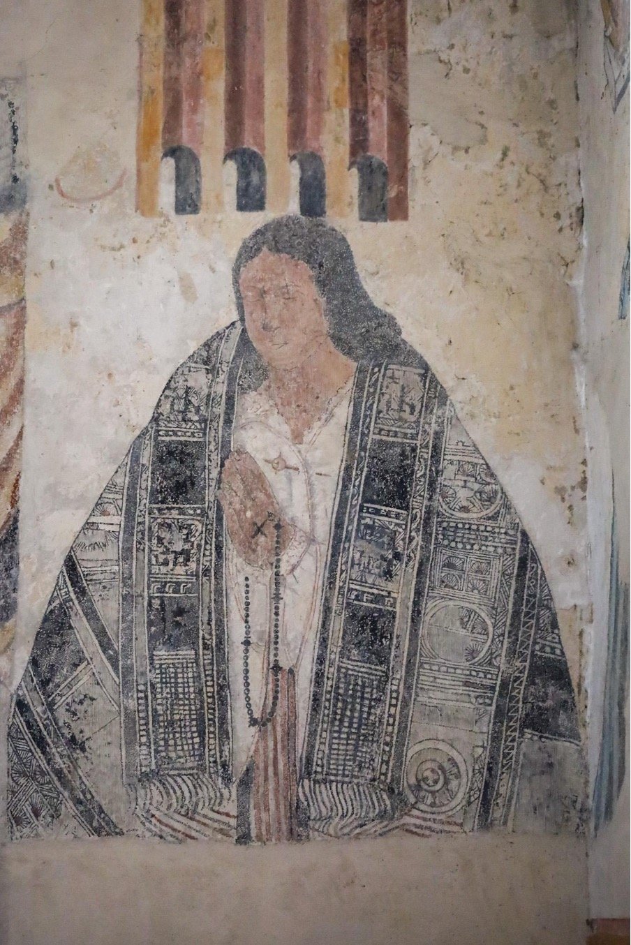 Mural de Cacica Muisca con textil indígena y rosario, simbolizando el encuentro de dos mundos en Sutatausa.